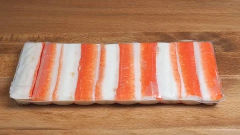 Crab sticks in packaging are placed on a wooden table. Fish delicacies for cooki 動画素材 346800462