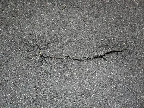 A crack on the asphalt surface of the road. View from above Stock Photos