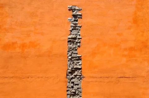 Crack of bricks in orange wall Stock Photos