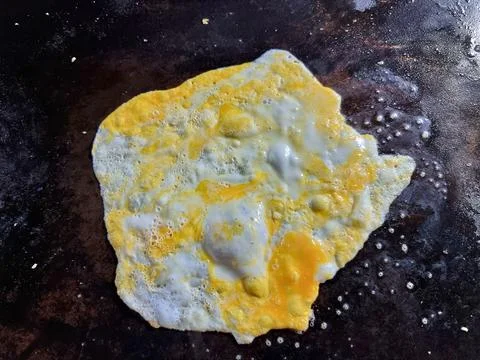 Crack an egg onto a hot black flat pan.Prepare to cook. Top view. Foto stock