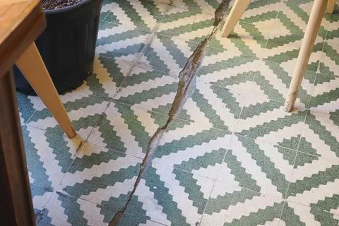 Crack in floor tiles in a room with patterned design Stock Photos