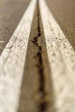 Crack in the middle of two white lines on the road Stock Photos