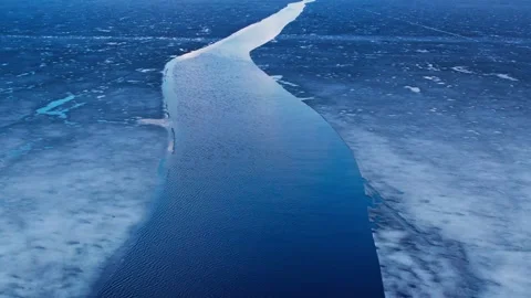 Crack of open water cutting through frozen ice on a vast blue icy landscape Video stock 299350762