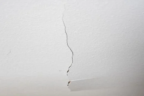 A crack in the white plastered ceiling. Concept of dilapidated housing and po Stock Photos