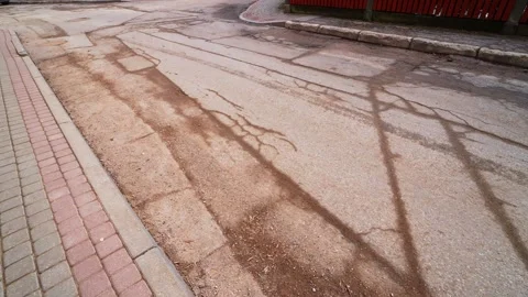 Cracked asphalt road with patchwork repairs, sand and salt along curb beside Vídeos de archivo 333655496