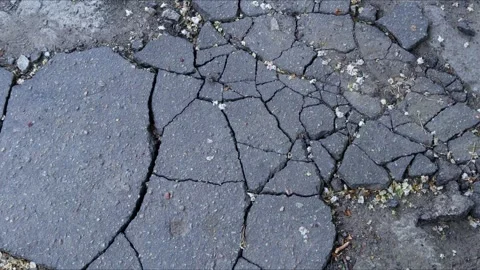 Cracked asphalt surface with multiple fissures, symbolizing wear and the ef.. Stock Footage 308403432