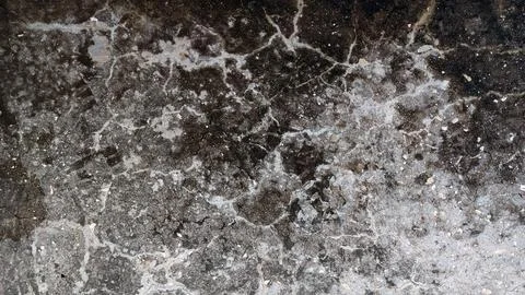 Cracked asphalt surface texture with white frost pattern 库存照片
