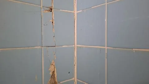 Cracked blue ceramic tile wall with structural damage corner Stock Photos