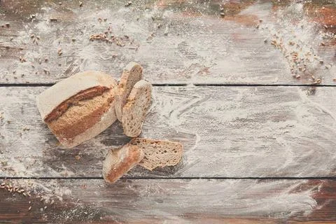 Cracked bread on rustic wooden table with flour dust Stock Photos