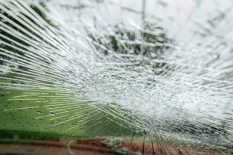 A cracked car windshield seen from the inside, with raindrops and a blurred Stock Photos