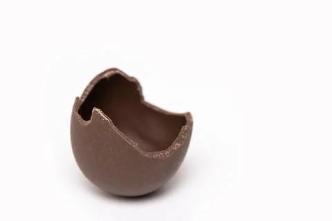 Cracked chocolate Easter egg on a white background, copy space. Half broken m Stock Photos