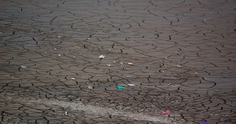 Cracked dry mud with scattered plastic waste and pollution texture Stock Footage 334001671