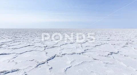 Cracked earth in a desert landscape against a blue sky. Stock Photos