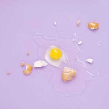 Cracked egg, eggshell with yolk isolated on purple background. Broken idea Foto stock