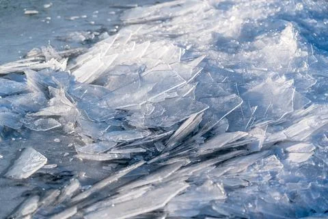 Cracked ice forms a textured surface on a frozen lake during winter in a co.. Stock Photos