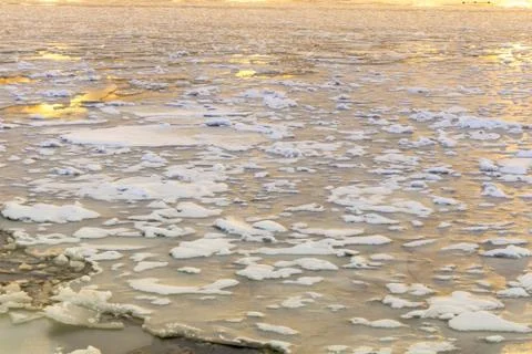 Cracked ice on the river. Spring warming, melting ice. Evening time Fotos de archivo