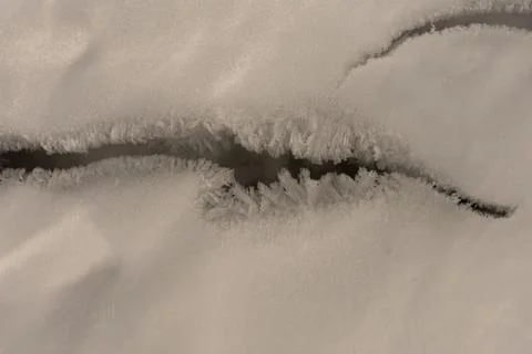 Cracked ice surface of a thick layer of ice on a lake with beautiful large Stock Photos