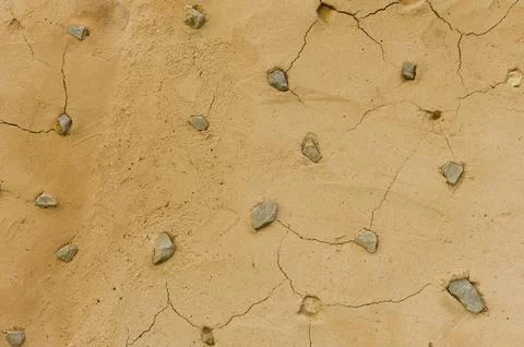 Cracked Mud Wall with Embedded Stones Texture Stock Photos