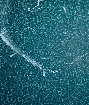 Cracked pattern on ice surface revealing intricate geometric shapes. 스톡 사진