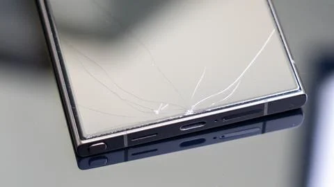 A cracked phone screen is reflected in a mirror Stock Photos