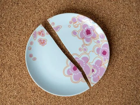 Cracked plate on the background of a cork table Foto stock