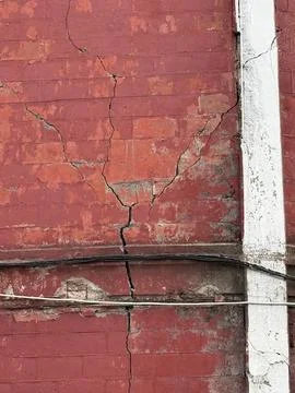 Cracked red brick wall with peeling paint and cables, suitable for texture .. Stock Photos