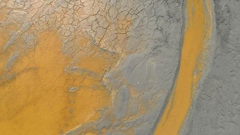 Cracked sludge with inserts of toxic yelow water at a mining disposal lake Stock Footage 106530978