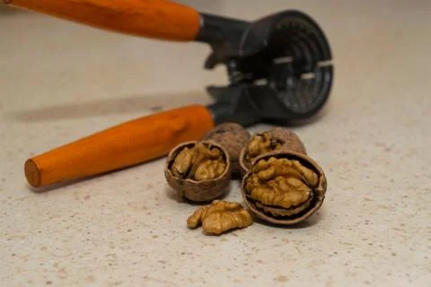 Cracked wallnuts with nut cracker in the background Stock Photos