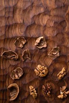 Cracked walnut shell and kernels scattered across the carved wooden board Stock Photos