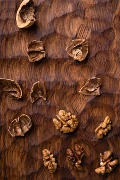Cracked walnut shell and kernels scattered across the carved wooden board Stock Photos