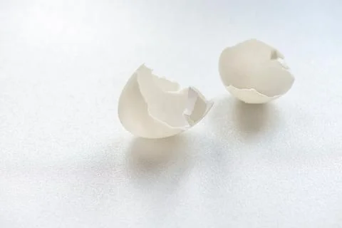 A cracked white eggshell on white background 스톡 사진
