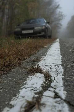 Cracked white solid line by the side of the asphalt road. In the background,  Foto stock