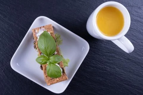 Cracker appetizer, basil on a white plate, next to orange juice Stock Photos