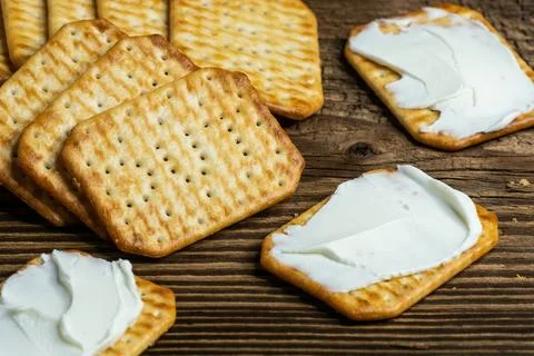 Crackers spread with cheese as a light snack on a wooden plank 写真素材