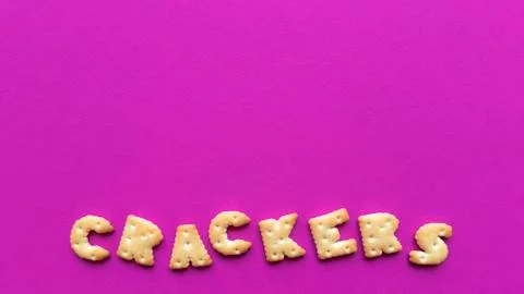 Crackers word on pink background. Simple flat lay with pastel texture and cop Stock Photos