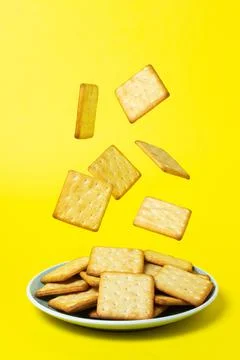 Crackers on a yellow background. Crackers fall into the plate. Stock Photos