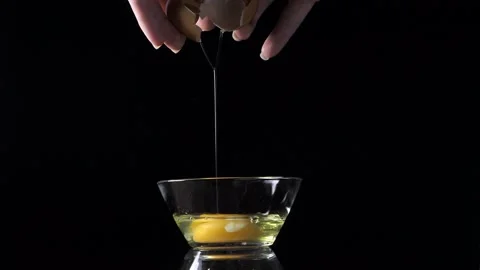 Cracking a chicken egg with hands on black background Video stock 167210855