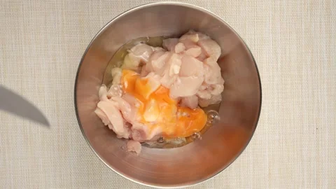 Cracking an Egg Into a Bowl of Chicken Pieces Stock Footage 342961097