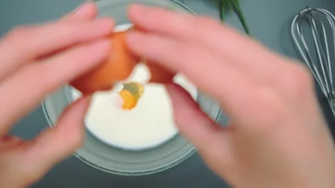 Cracking an egg into a deep bowl of milk Stock Footage 252385604