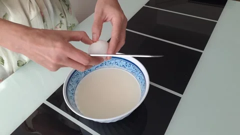 Cracking an egg into a dough slow-motion video Stock Footage 286733194