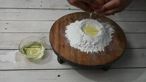 Cracking an egg into flour to make bread according to traditional recipe. Stock Footage 209134001