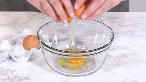 Cracking egg into glass bowl 스톡 사진