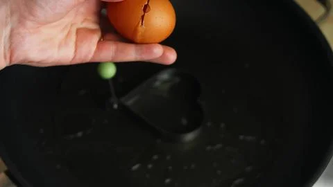 Cracking an Egg into a Heart Shaped Mold — Tight Close Up 스톡 사진