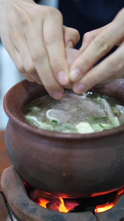 Cracking Egg Into Hot Shabu Pot on Clay Stove Video stock 320768883