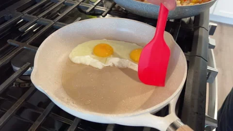 Cracking egg into non-stick skillet on stove Stock Footage 344937780