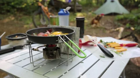 Cracking Eggs for Breakfast Scramble while Camping with Bike, Tent, and Dog 库存影片 64652336