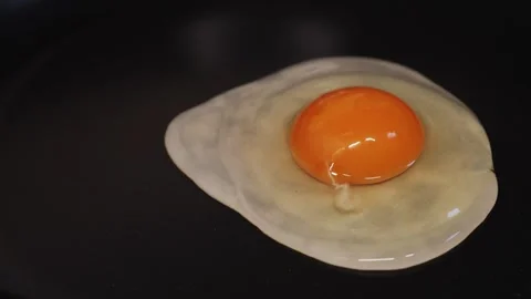 Cracking eggs in a frying pan on the stove preparing scrambled eggs in the Stock Footage 310601364