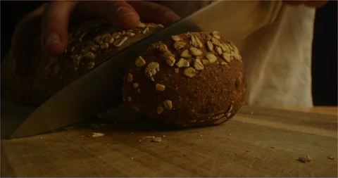 Cracking fresh brown bread with cereals into camera Stock-Footage 126296242