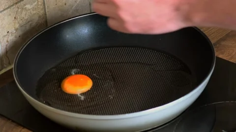Cracking fresh egg into hot frying pan for home cooking breakfast process Stock Footage 343258888
