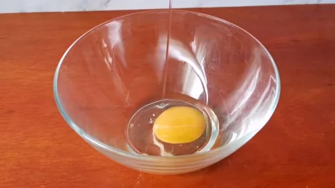 Cracking Fresh Raw Egg in a Glass Bowl Stock Footage 234882105